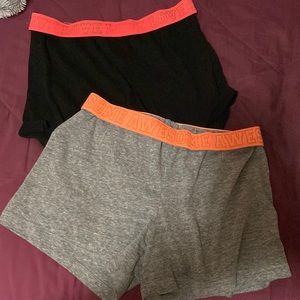 2 kids shorts, 1 black with pink band and 1 gray with orange band